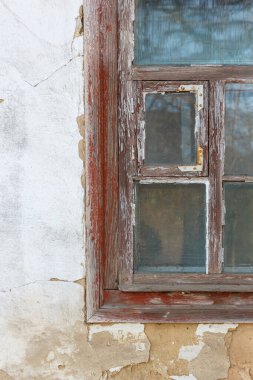 Kırsal, soyulan ahşap pencere çerçevesinin detaylı görüntüsü. Çatlamış bir cam ve çürüyen bir alçı ve taş duvarda..