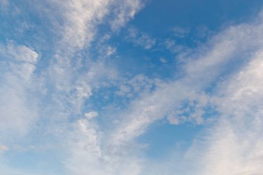 Narin bir sirrus ve dağınık beyaz bulutlarla aydınlık ve havadar bir atmosfer yaratan berrak mavi bir gökyüzü..