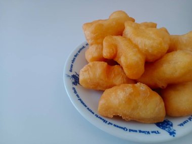 Patongo, the 5th most delicious and best street food in the world and many places in the world. According to the TasteAtlas rating, placed on a plate on a white background with copy space, crispy yellow, juicy, appetizing with copy space.