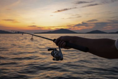 Gün batımında deniz dibinde oltayı tutan el.