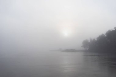 İsveç kıyılarında küçük bir ev ve kışın yoğun sisi aşan güneş.