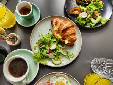 Jambonlu kahvaltı tabakları ve tabak ve kahveli yumurta kruvasanı.