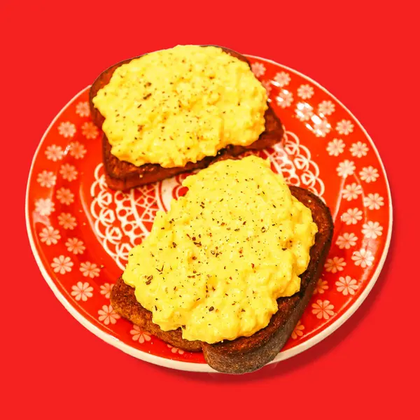 Kırmızı tabakta çırpılmış yumurtalı tost, üst manzara.