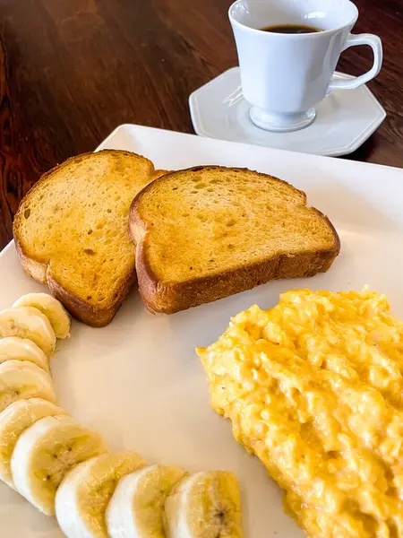 breakfast with scrambled eggs, bananas and toast