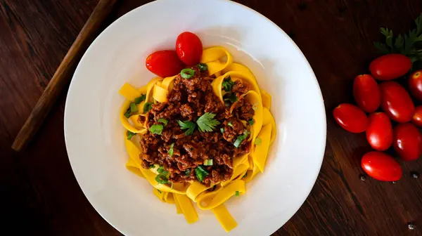 Tagliatelle bolonez makarnası kıymalı ve domatesli ahşap zemin