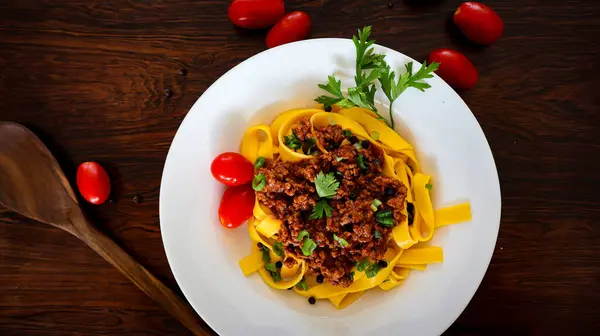 Tagliatelle bolonez makarnası kıymalı ve domatesli ahşap zemin