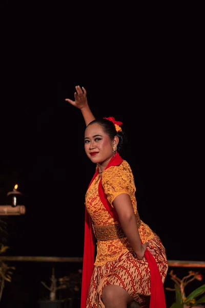 Asian woman performing a traditional dance called jaipong in Indonesia with a yellow dress and red scarf at the dance festival