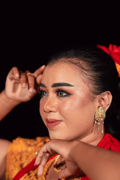 夜にオレンジのドレスと黄金のイヤリングを身に着けている間 彼女の顔に化粧をしたインドネシアの女性からの鋭い視線 — ストック写真