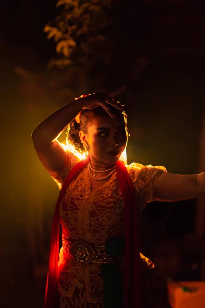 节日期间 一名身着传统橙色衣服的巴厘妇女在灯光前跳舞时的侧影 — 图库照片
