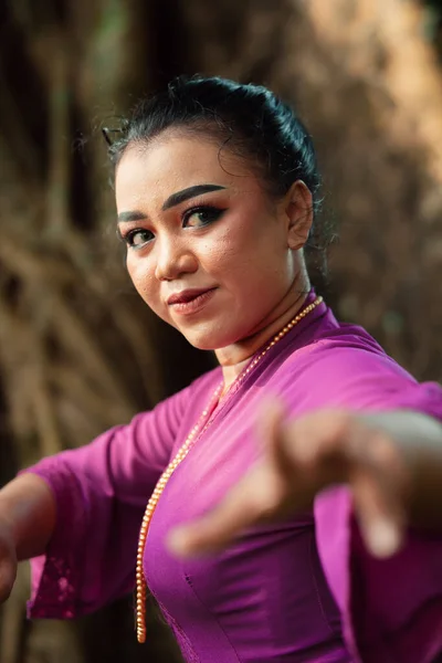 化粧をしたジャワ人女性の顔と ケバヤと呼ばれる伝統的な紫色のドレスは ジャングルの中で宝石で踊り ポーズをとっています — ストック写真