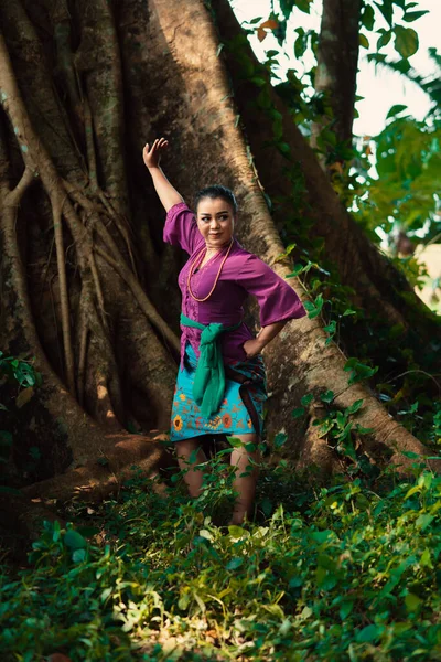 Индонезийская Женщина Смело Позирует Поднимая Руки Фиолетовом Платье Стоя Лесу — стоковое фото