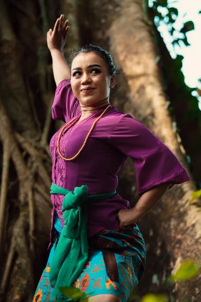 Indonezyjska Kobieta Odważnie Pozuje Podnosząc Ręce Fioletowej Sukience Stojąc Lesie — Zdjęcie stockowe