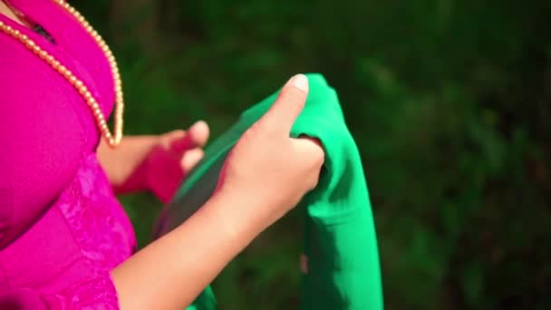 日中はピンクのドレスとメイクで彼女の手の中に緑のスカーフを保持しながら 森の中を歩くアジアの女性 — ストック動画