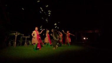 Balili kadınlar ayini dansla kutlarken, bir adam da festivalin içinde sahnede dans eden dansçı arasında gökyüzüne para saçıyor.
