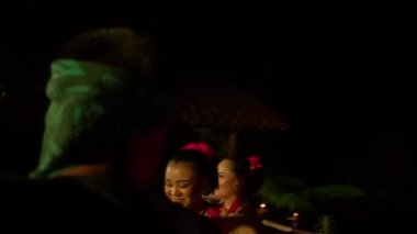 Balili kadınlar ayini dansla kutlarken, bir adam da festivalin içinde sahnede dans eden dansçı arasında gökyüzüne para saçıyor.