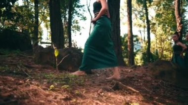 an Asian woman in a green dress approached a man when he was hanging out with his girlfriend in the middle of the forest in the afternoon