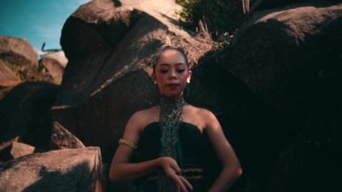 Asian woman in traditional green dress meditating lonely in peacefully in front of the big rock at the mountain during the morning