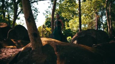 Asian queen standing on the big rock while wearing a green dress inside the jungle during the daylight