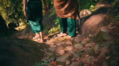 Asian couple walking down the hill above the mountain with a forest in the background while chatting together in green clothes during the day