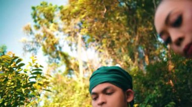 Asian couple walking down the hill above the mountain with a forest in the background while chatting together in green clothes during the day