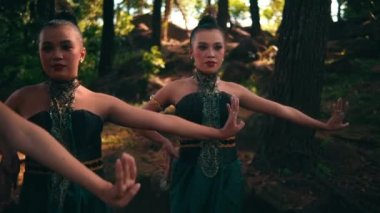 Bir grup Endonezyalı kadın gün ışığında köydeki festivalde gösteri yaparken yeşil elbiseler içinde dans ediyorlar.