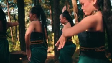 Bir grup Endonezyalı kadın gün ışığında köydeki festivalde gösteri yaparken yeşil elbiseler içinde dans ediyorlar.