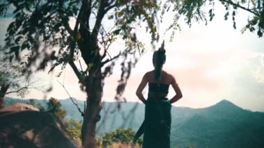 Asian woman with a long dress and black hair standing in front of the canyon to enjoy the view from the top of the mountain during the daylight