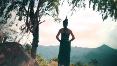 Asian woman with a long dress and black hair standing in front of the canyon to enjoy the view from the top of the mountain during the daylight