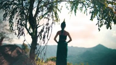 Asian woman with a long dress and black hair standing in front of the canyon to enjoy the view from the top of the mountain during the daylight
