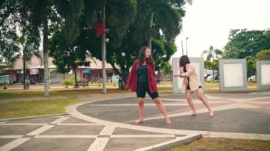 a group of women dancing contemporarily behind a sad woman in a park during the day