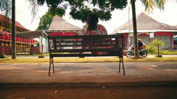 Asian Woman Wakes Park Bench Big Shady Tree Alone Noon — Stockvideo