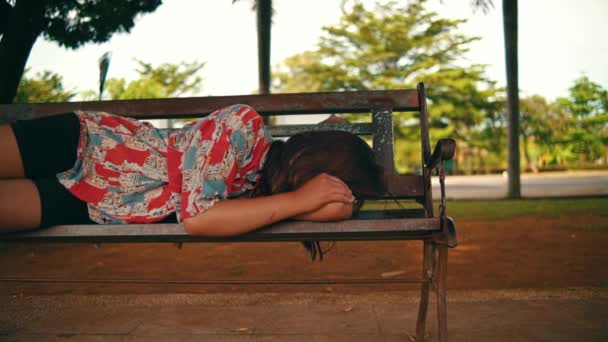 一个亚洲女人白天一个人躺在一棵巨大的树阴下的公园长椅上 — 图库视频影像