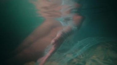 the hands and feet of an Asian woman diving in the sea with a cloth dangling while swimming on the beach in the morning