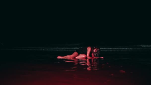 一个身穿黑色衣服 浑身湿透的亚洲女人 晚上躺在沙滩上 被波浪缠绕着 — 图库视频影像