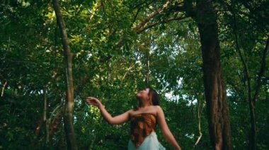 An Asian woman was very impressed by the beauty of a green tree in a tropical rainforest on an island while on vacation during the day