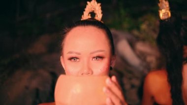 Güzel bir Asyalı kadın, gece köyde düzenlenen bir festivalde dans gösterisi için bambu maskesi takıyor.