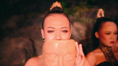 Güzel bir Asyalı kadın, gece köyde düzenlenen bir festivalde dans gösterisi için bambu maskesi takıyor.