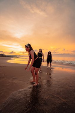 a group of Indonesian women doing ballet movement exercises together very flexibly on the beach in the afternoon