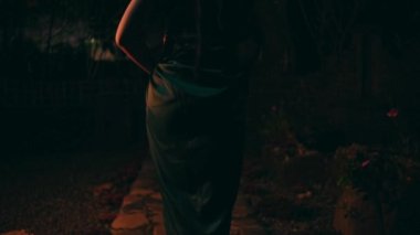 Gece eve dönerken köyün ortasında yalnız başına yürüyen üzgün bir Asyalı kadın.