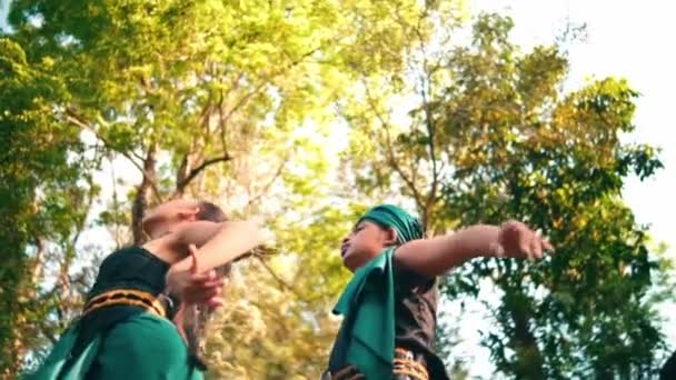 朝早く森の真ん中で緑の伝統的な服を着て踊るアジアの女性と男性 — ストック動画