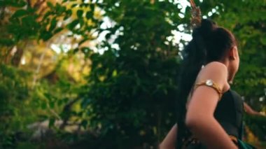 An Asian woman approaches someone with an angry expression while wearing green clothes and makeup in the middle of the forest in the morning