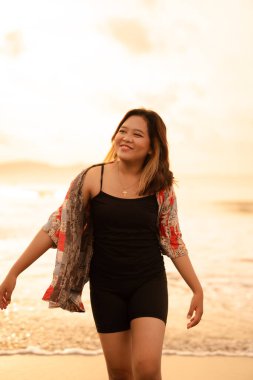 An Indonesian woman with blonde hair and a red shirt was enjoying her holiday by the beach when visiting Bali at sunset