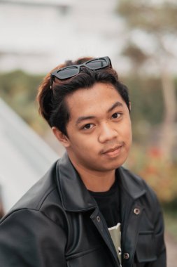 the face of a very silly Asian man with sunglasses on his head while relaxing in a cafe during the day