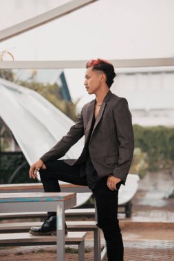 a grown man in a gray suit posing around a cafe table in a very manly and masculine manner before entering the office at noon