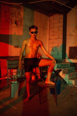 a gay man in black pants is waiting for his boyfriend in an old building at night