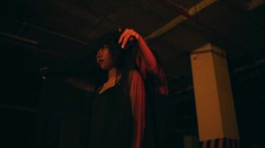 a woman in a black dress puts on a black robe while performing a devil worship ritual in the dark at night