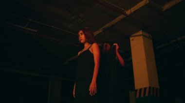 a woman in a black dress puts on a black robe while performing a devil worship ritual in the dark at night