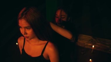a woman combing the blonde hair of a Satanist in the background of the pentagram at night