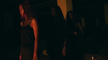 a group of satanic women perform a spirit summoning ritual in the middle of a satanic altar at night