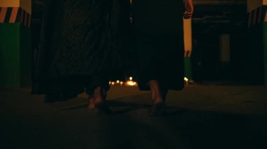 a couple of Satanists in black robes walked together to the pentagram altar to perform the ritual at night